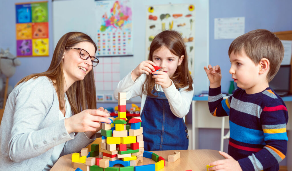 Teacher and Kids Playing Together with Colorful Toy Building Blocks